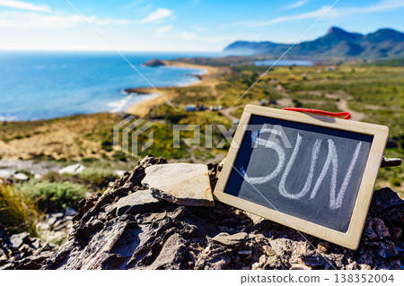 Black board with word sun against sea coast Black board with word sun against sea coast 138352004
