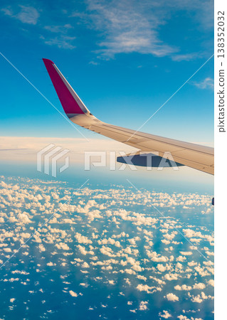 View from an airplane window to wing and clouds 138352032