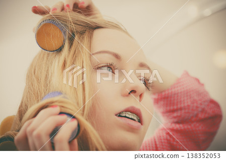 Woman curling her hair using rollers 138352053