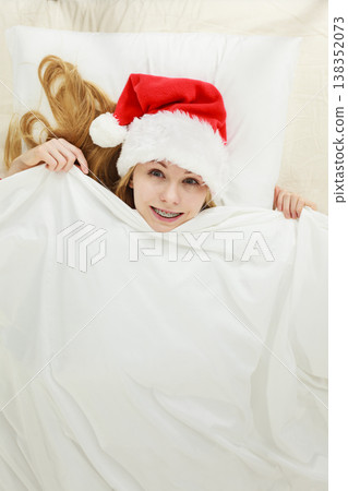 Happy woman wearing pajamas and Santa Claus hat 138352073
