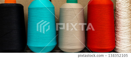 Colorful textile thread spools stacked warehouse show fiber production materials visible texture twist pattern detail. Circular rolls manufacturing process material quality order consistency. 138352105