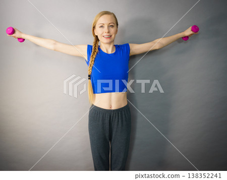 Teenage woman working out at home with dumbbell 138352241
