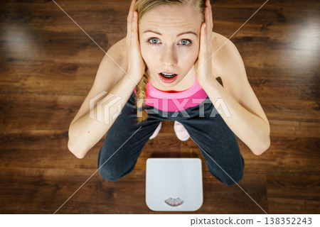 Scared woman on bathroom scale machine 138352243