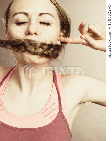 Woman covering her mouth with blonde braid 138352245