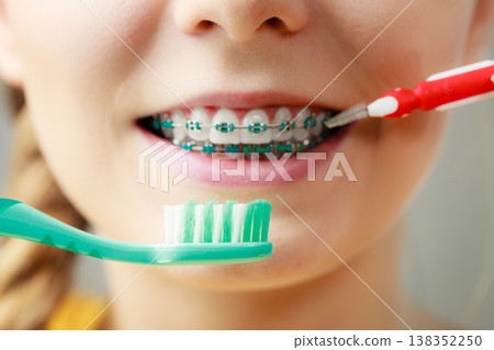 Girl with teeth braces using interdental and traditional brush Girl with teeth braces using interdental and traditional brush 138352250