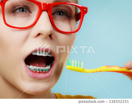 Woman with teeth braces using brush 138352251