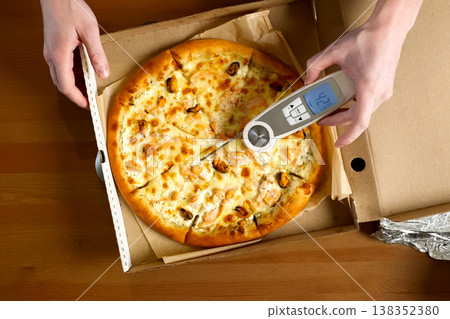measuring pizza temperature with a thermometer 138352380