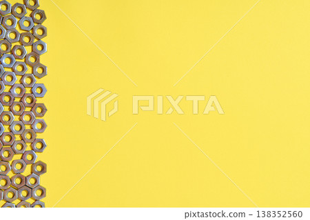 Vertical metal nuts border on yellow background. Vertical metal nuts border on yellow background. 138352560