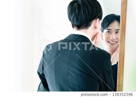 一名身穿西裝的男子在鏡子前整理儀容。 138352596
