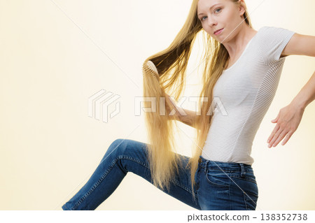 Blonde girl brushing her long hair Blonde girl brushing her long hair 138352738