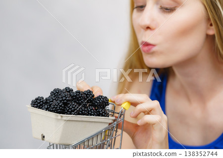 Girl holds blackberry fruits in shopping cart Girl holds blackberry fruits in shopping cart 138352744