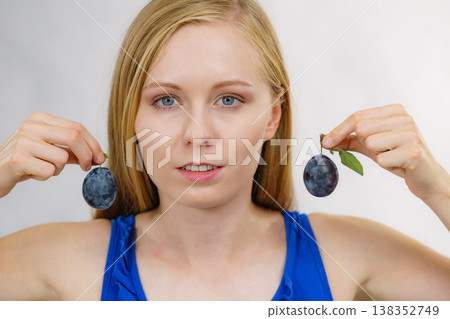Girl holds plum fruit to her ear Girl holds plum fruit to her ear 138352749