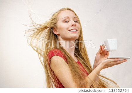 Blonde girl blowing hair holds coffee cup Blonde girl blowing hair holds coffee cup 138352764