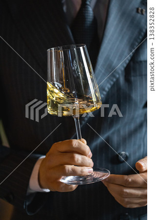 Swirling white wine in glass held by sommelier Swirling white wine in glass held by sommelier 138352828