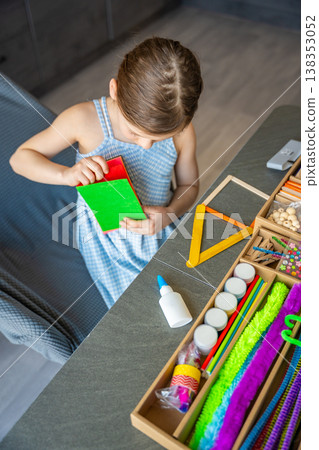 Little girl choosing colorful felt sheets for craft project at table with creative supplies. Kids creativity development fine motor skills and learning through play concept. Little girl choosing colorful felt sheets for craft project at table with creative supplies. Kids creativity development fine motor skills and learning through play concept. 138353052