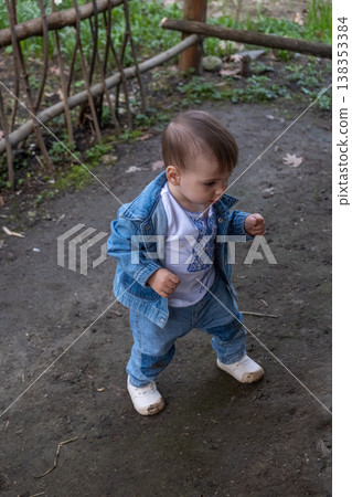 Toddler taking first steps outdoors near rustic wooden fence Toddler taking first steps outdoors near rustic wooden fence 138353384