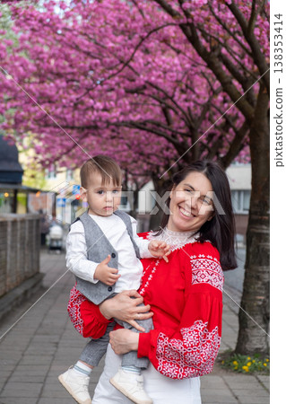 Smiling mother holding toddler under cherry blossom trees Smiling mother holding toddler under cherry blossom trees 138353414