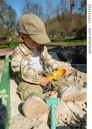 Toddler playing in sandbox at park on sunny day Toddler playing in sandbox at park on sunny day 138353422