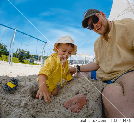 Father and toddler playing in sandbox at playground 138353426