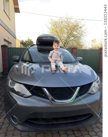Toddler sitting on hood of gray suv in driveway Toddler sitting on hood of gray suv in driveway 138353443