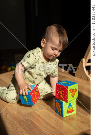 Toddler playing with colorful soft blocks on sunlit floor Toddler playing with colorful soft blocks on sunlit floor 138353445