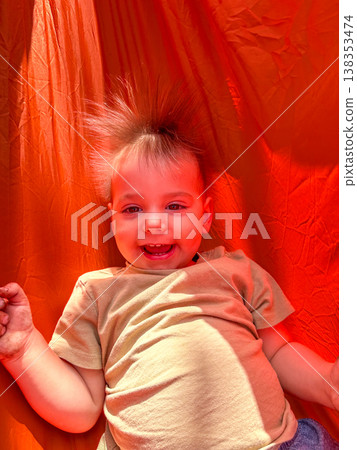 Smiling toddler on bright orange playground slide 138353474