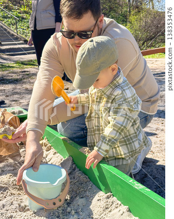 Father and son playing in sandbox outdoors on sunny day Father and son playing in sandbox outdoors on sunny day 138353476