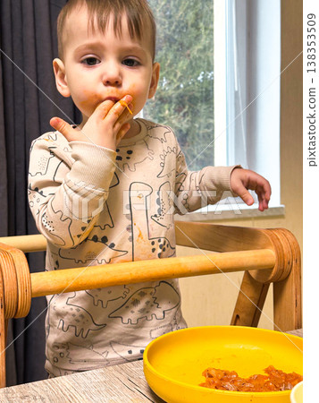Toddler self-feeding messy meal in high chair 138353509