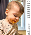 Toddler eating finger food with messy face indoors 138353510