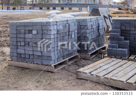 Concrete paving blocks stacked on wooden pallets at a construction site. 138353515