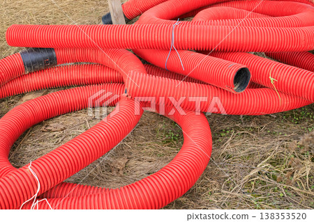 Red corrugated plastic pipes for underground cable protection at a construction site. Red corrugated plastic pipes for underground cable protection at a construction site. 138353520