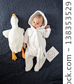 Newborn baby in white hooded onesie with plush goose toy 138353529