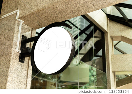 A storefront features a circular sign with no logo. The entrance is clean and has large glass panels. 138353564