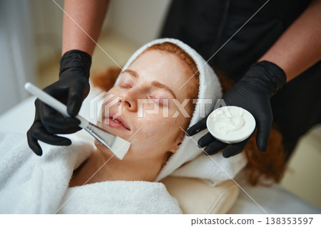 Woman receiving a facial treatment with cream application in a spa Woman receiving a facial treatment with cream application in a spa 138353597