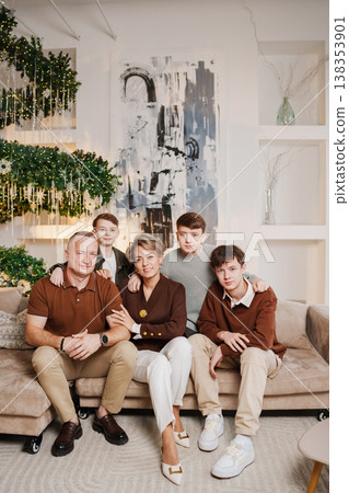 Family poses together for a photo in a modern living room setting Family poses together for a photo in a modern living room setting 138353901