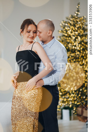 Couple dances together in front of a decorated Christmas tree 138353906