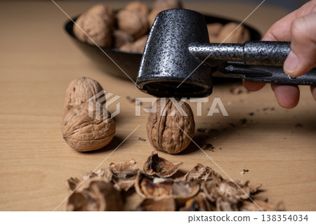 Cracking walnuts with a metal nutcracker tool Cracking walnuts with a metal nutcracker tool 138354034