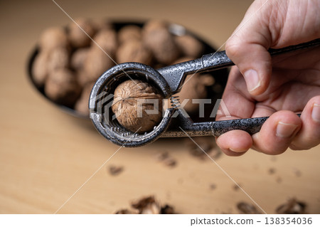 Cracking walnuts with a metal nutcracker tool 138354036