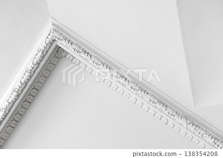 Elegant white interior details, decorative plaster ceiling corner with ornate molding 138354208