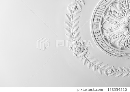 Ornate white plaster ceiling medallion with decorative floral molding 138354210