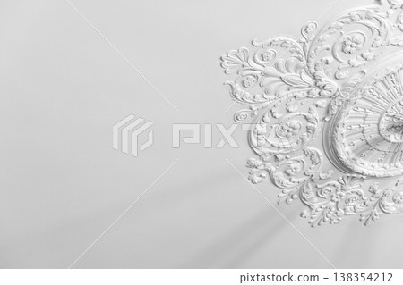 Ornate white plaster ceiling medallion with intricate floral molding and classical details Ornate white plaster ceiling medallion with intricate floral molding and classical details 138354212