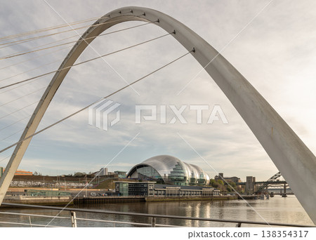 Framed by the graceful, soaring white arch of the Gateshead Millennium Bridge, the riverside reveals a masterclass in modern engineering. At the heart of the vista sits The Glasshouse (formerly Sage Framed by the graceful, soaring white arch of the Gateshead Millennium Bridge, the riverside reveals a masterclass in modern engineering. At the heart of the vista sits The Glasshouse (formerly Sage 138354317