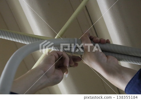 The task of bundling and securing multiple corrugated tubes to the ceiling beams. 138355184