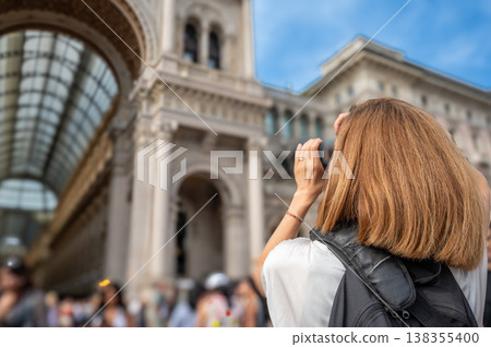 Woman traveler exploring milan, photographing the historic galleria vittorio emanuele ii with a camera, immersed in the culture and architecture of italy 138355400