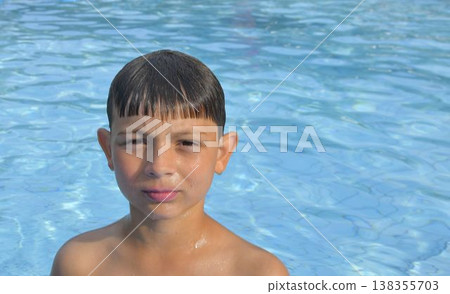 A boy in the water at a public swimming pool. A little kid at the edge of the pool. Copy space. The concept of summer, summer vacations, and leisure time. A boy in the water at a public swimming pool. A little kid at the edge of the pool. Copy space. The concept of summer, summer vacations, and leisure time. 138355703