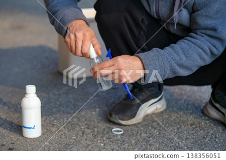 Man pouring disinfectant alcohol into a spray bottle 138356051
