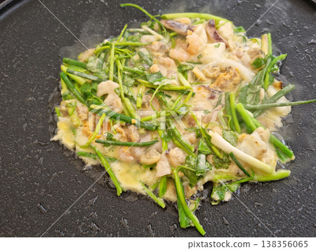 This is water parsley pancake being cooked in a frying pan. This is water parsley pancake being cooked in a frying pan. 138356065