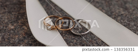 Banner Wedding rings on white ribbon on dark stone surface 138356331
