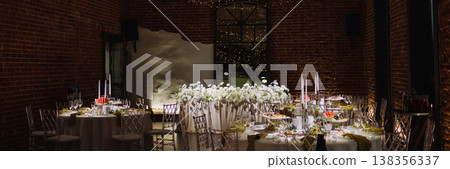 Banner Wedding banquet tables with floral decor in loft hall with brick walls and garland lights Banner Wedding banquet tables with floral decor in loft hall with brick walls and garland lights 138356337