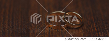 Banner Two gold wedding rings on dark wooden surface with dark background 138356338